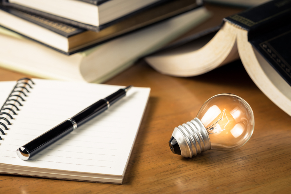 Small,Light,Bulb,Glowing,On,The,Desk,,With,Notebook,And